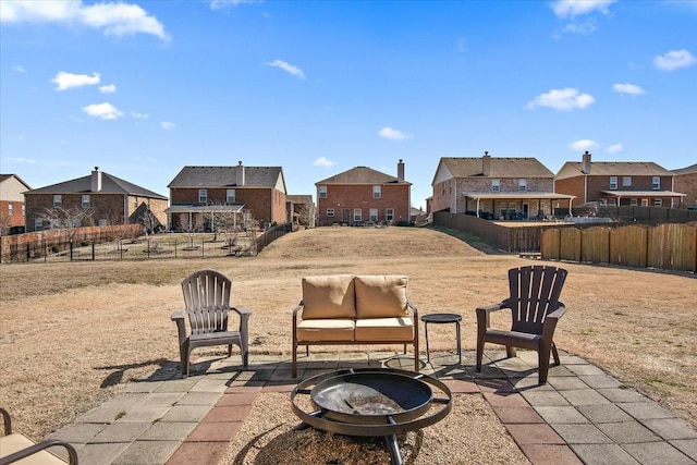 view of patio with an outdoor fire pit, fence, and a residential view