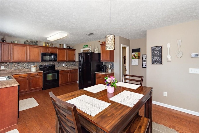 kitchen featuring dark wood-style floors, visible vents, backsplash, and black appliances