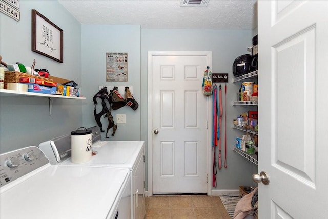 clothes washing area featuring a textured ceiling, light tile patterned flooring, laundry area, visible vents, and washing machine and clothes dryer