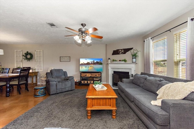 living area with finished concrete flooring, visible vents, a ceiling fan, a textured ceiling, and a fireplace