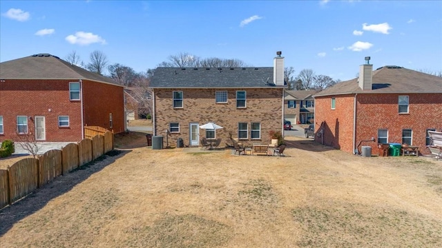 rear view of property featuring a chimney and brick siding