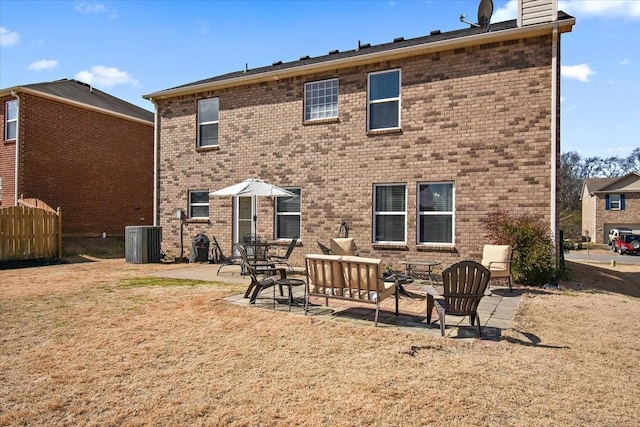 rear view of property featuring brick siding, a yard, a patio, a chimney, and central air condition unit