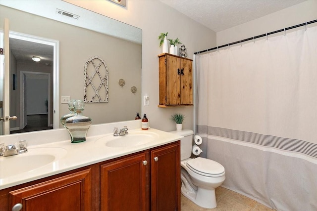 bathroom featuring a textured ceiling, double vanity, a sink, and visible vents