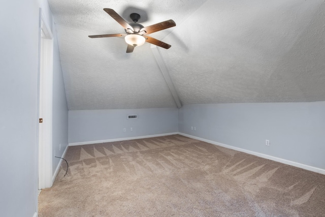 bonus room with baseboards, visible vents, lofted ceiling, a textured ceiling, and carpet flooring