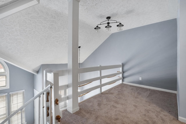 interior space featuring a textured ceiling, carpet flooring, and baseboards