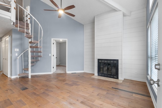 unfurnished living room featuring baseboards, a fireplace with flush hearth, ceiling fan, stairway, and wood finished floors