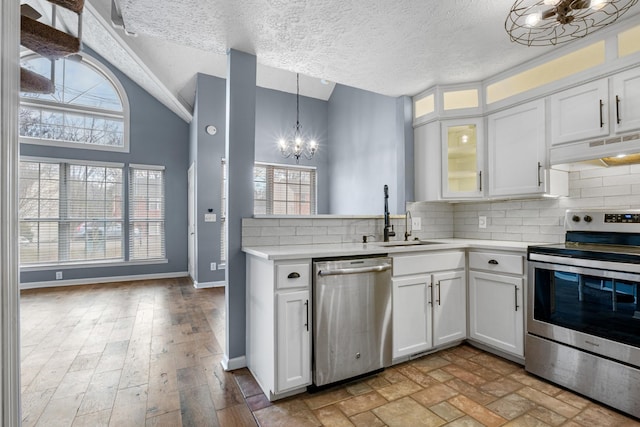 kitchen featuring light countertops, backsplash, appliances with stainless steel finishes, white cabinetry, and under cabinet range hood