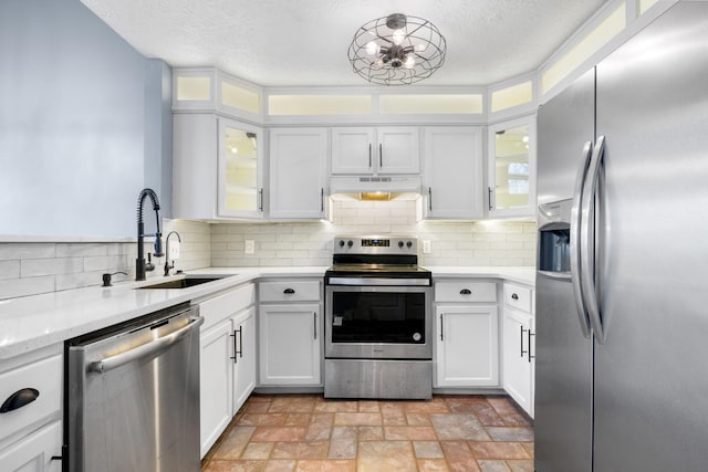 kitchen featuring stainless steel appliances, backsplash, a sink, and under cabinet range hood