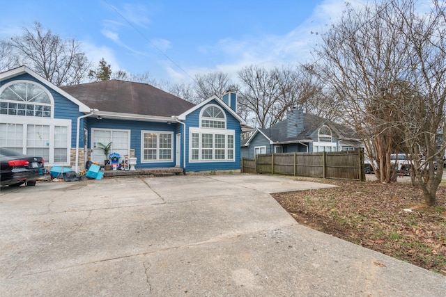 exterior space with driveway, a shingled roof, and fence