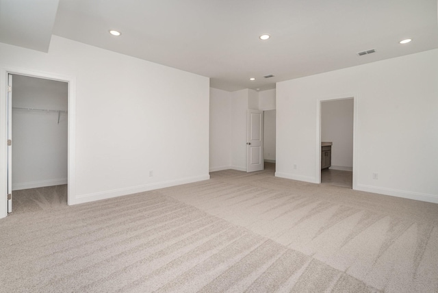 unfurnished bedroom with recessed lighting, visible vents, a spacious closet, and carpet flooring