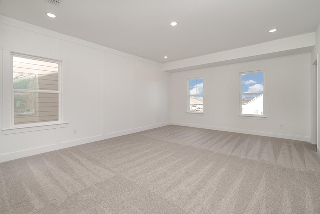 unfurnished room featuring recessed lighting, light carpet, a decorative wall, and baseboards