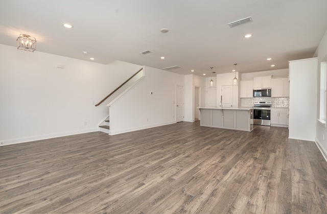 unfurnished living room featuring stairway, wood finished floors, visible vents, and recessed lighting