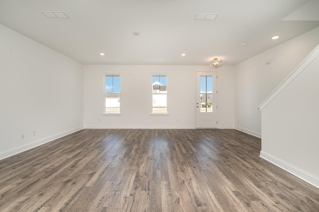 unfurnished living room with dark wood-style floors, baseboards, visible vents, and a wealth of natural light