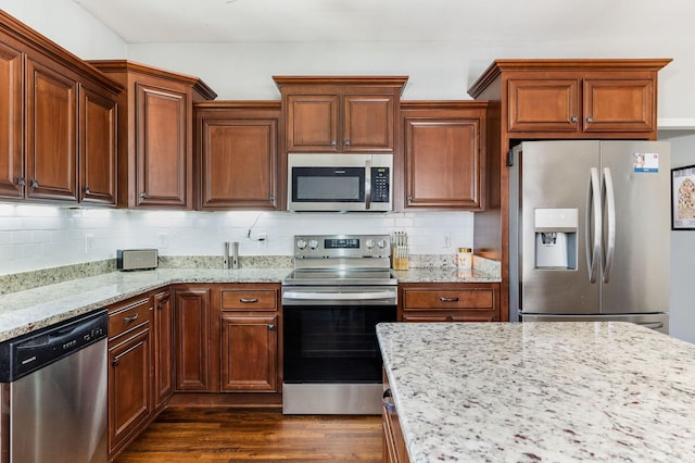 kitchen featuring stainless steel appliances, light stone countertops, dark wood-type flooring, and tasteful backsplash