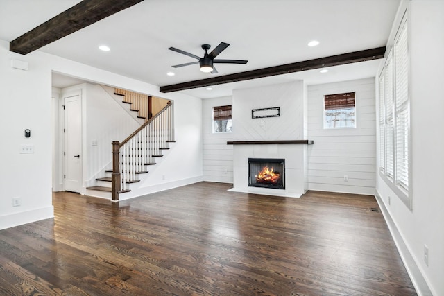 unfurnished living room with recessed lighting, a fireplace with flush hearth, wood finished floors, stairs, and beam ceiling