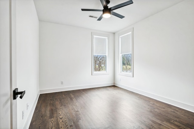 empty room featuring dark wood-type flooring, visible vents, baseboards, and a ceiling fan