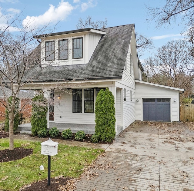 view of front facade with driveway, covered porch, an attached garage, and a shingled roof