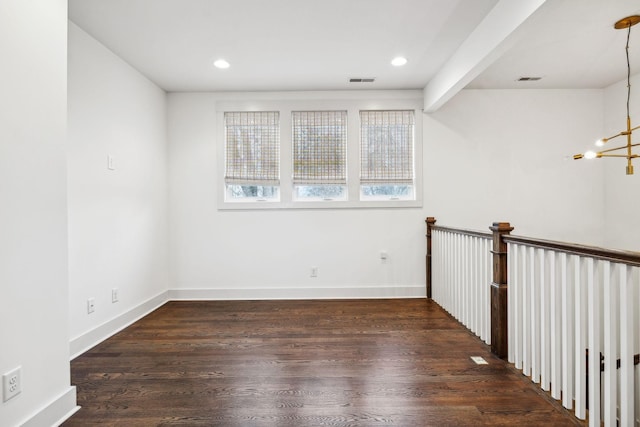 spare room featuring wood finished floors, visible vents, and baseboards