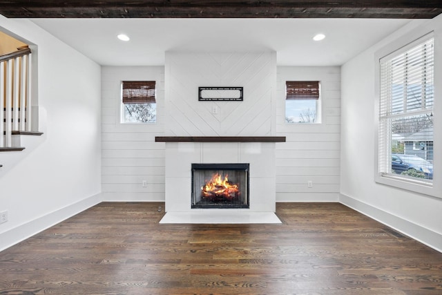 unfurnished living room featuring dark wood-style floors, stairway, a fireplace with flush hearth, and baseboards