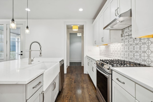 kitchen featuring under cabinet range hood, decorative backsplash, stainless steel appliances, and light countertops