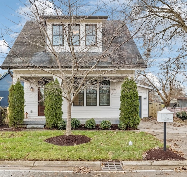 view of front of house featuring a front lawn and roof with shingles