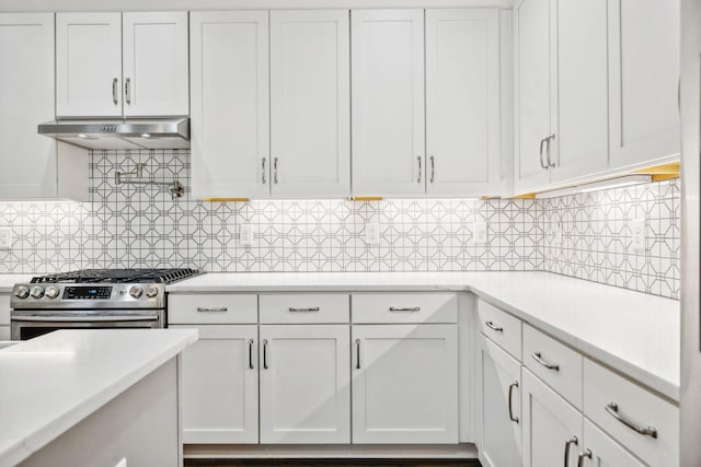 kitchen with under cabinet range hood, white cabinets, light countertops, decorative backsplash, and stainless steel gas stove