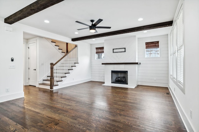 unfurnished living room with beam ceiling, stairway, a fireplace with flush hearth, wood finished floors, and baseboards