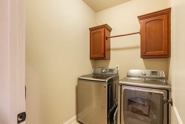 laundry room with washing machine and dryer, cabinet space, and baseboards