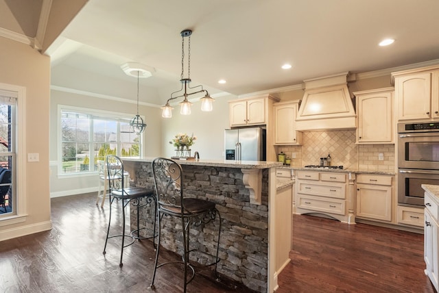 kitchen featuring light stone counters, appliances with stainless steel finishes, a breakfast bar, premium range hood, and backsplash