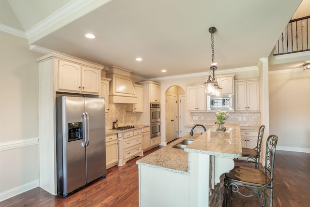 kitchen with arched walkways, dark wood finished floors, stainless steel appliances, ornamental molding, and a sink