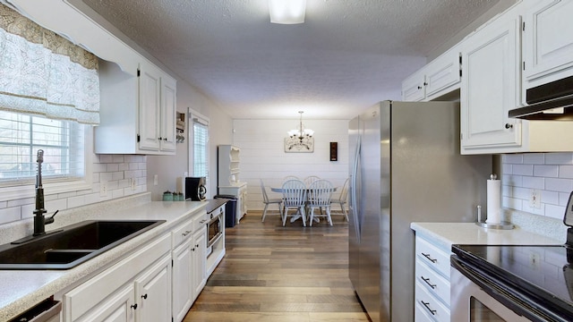 kitchen with a sink, white cabinets, light countertops, appliances with stainless steel finishes, and dark wood-style floors