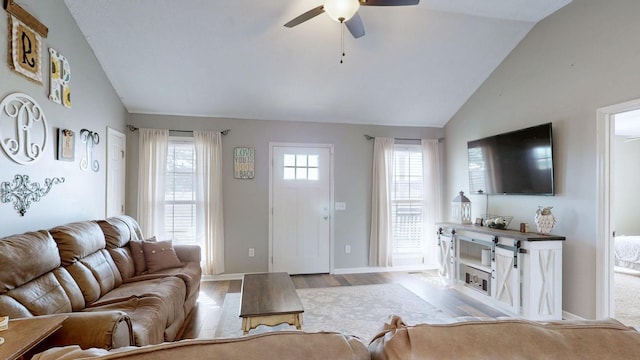 living area with lofted ceiling, wood finished floors, a ceiling fan, and a healthy amount of sunlight