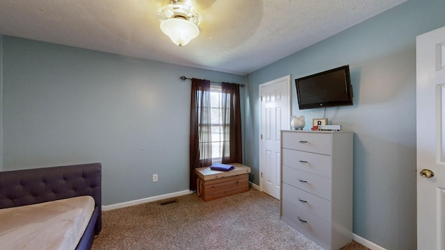 bedroom with a textured ceiling, light colored carpet, visible vents, and baseboards