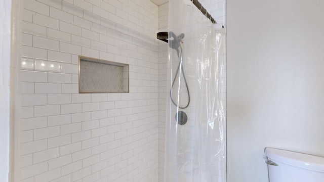 full bath featuring tiled shower and toilet