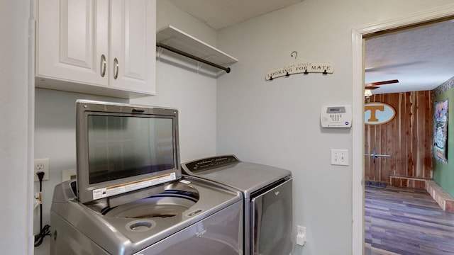 clothes washing area with cabinet space, washer and clothes dryer, and wood finished floors