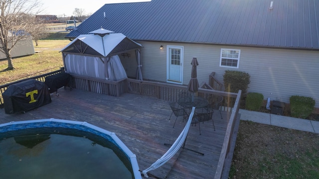 back of house with metal roof, a wooden deck, and a hot tub