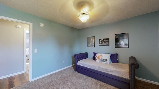 carpeted bedroom featuring a textured ceiling and baseboards