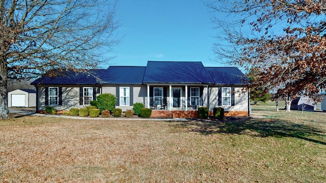 ranch-style home with metal roof, a front lawn, a porch, and an outbuilding