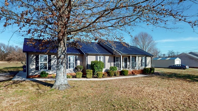 single story home with covered porch, an outdoor structure, a front lawn, and metal roof