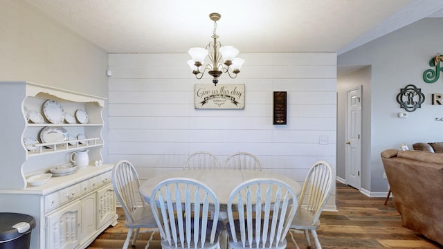 dining room featuring wooden walls, baseboards, an accent wall, wood finished floors, and a notable chandelier