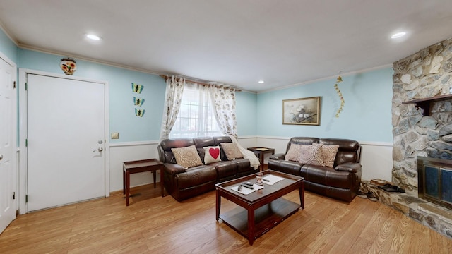 living area with light wood-style floors, a fireplace, and ornamental molding