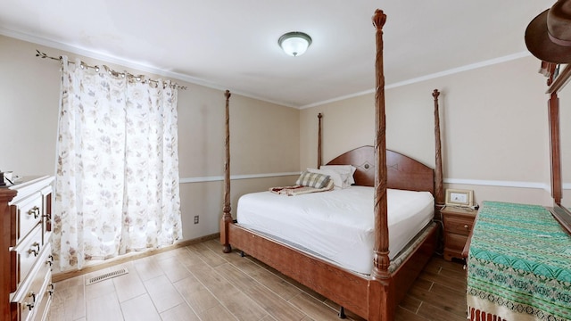 bedroom featuring wood tiled floor, visible vents, crown molding, and baseboards