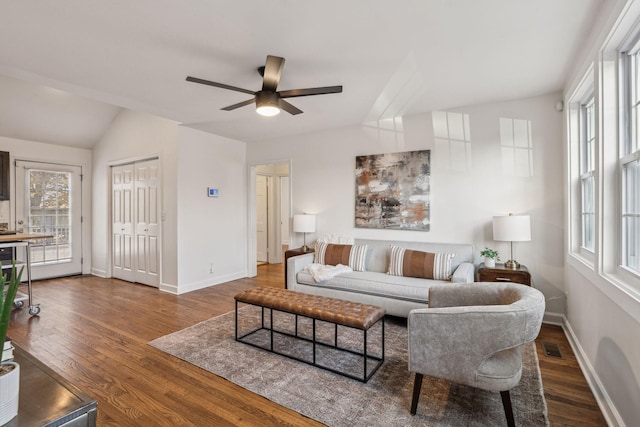 living area with visible vents, vaulted ceiling, ceiling fan, wood finished floors, and baseboards