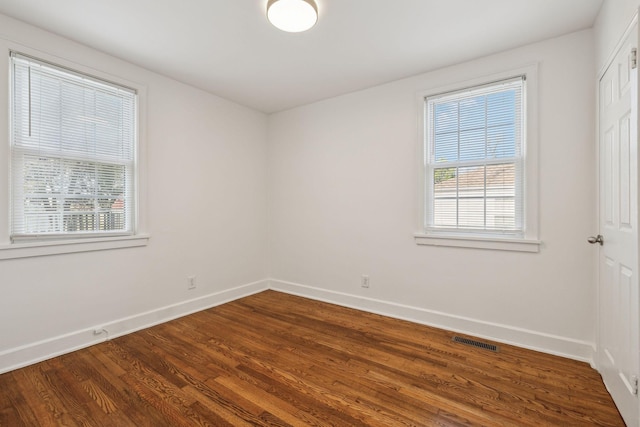 unfurnished room with dark wood-style floors, baseboards, and visible vents