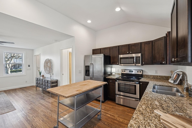 kitchen with appliances with stainless steel finishes, dark wood-style flooring, a sink, and dark brown cabinetry