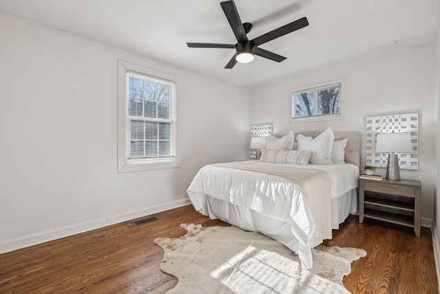 bedroom featuring baseboards, multiple windows, visible vents, and wood finished floors