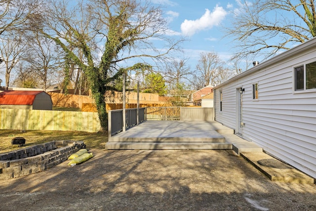 view of yard featuring a storage unit, fence, an outbuilding, and a wooden deck