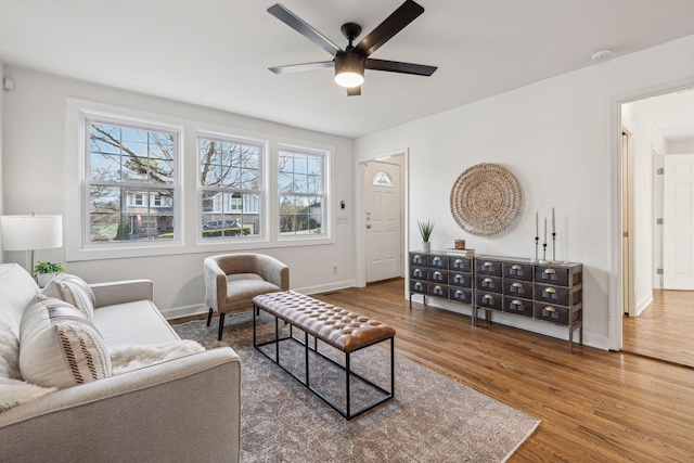 living area with ceiling fan, baseboards, and wood finished floors