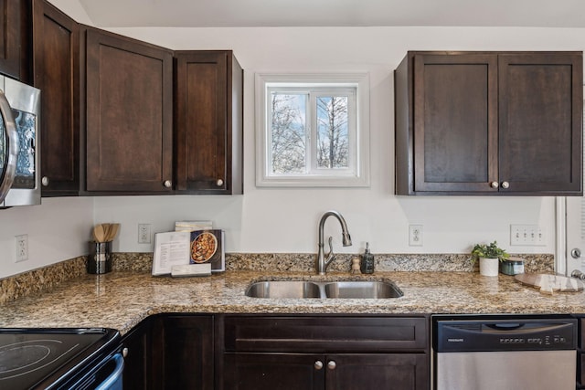 kitchen with dark brown cabinets, appliances with stainless steel finishes, a sink, and light stone counters