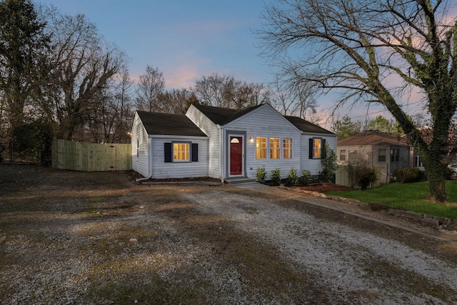 view of front of home with fence and dirt driveway